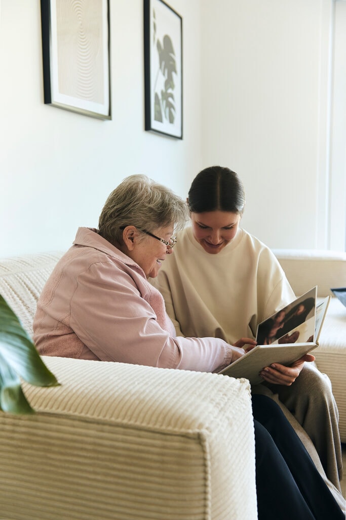Kundin zeigt der Pflegefachkraft ihre Fotoalben und erzählt dabei die Gesichten aus der Vergangenheit