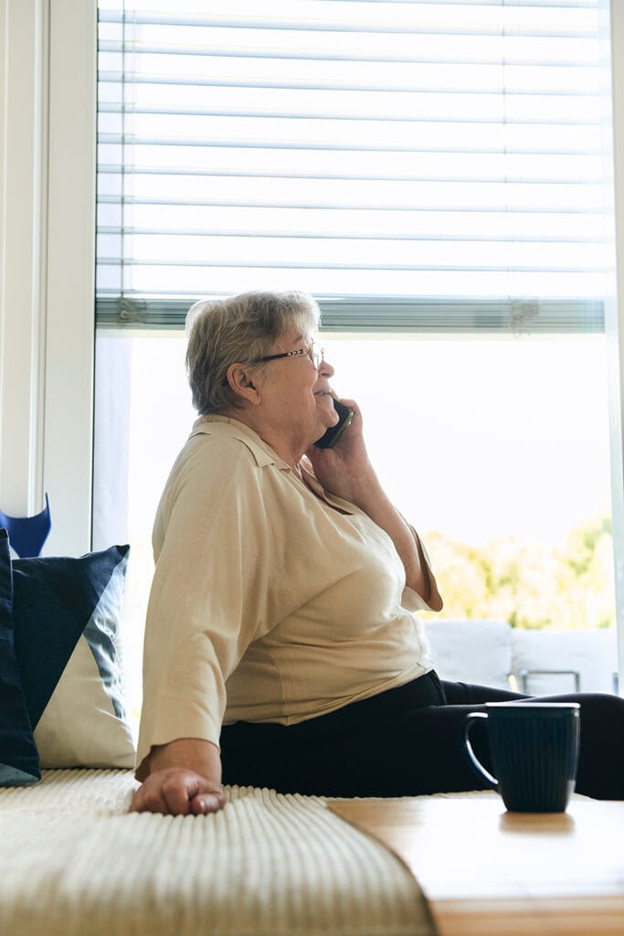 Pflegebedürftige Kundin telefoniert mit ihren Angehörigen und lächelt dabei