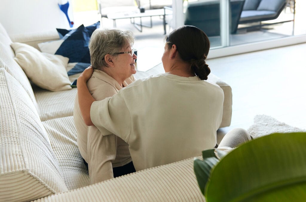 Pflegebedürftige Kundin und Pflegehelferin verbringen gemeinsam Zeit auf der Couch